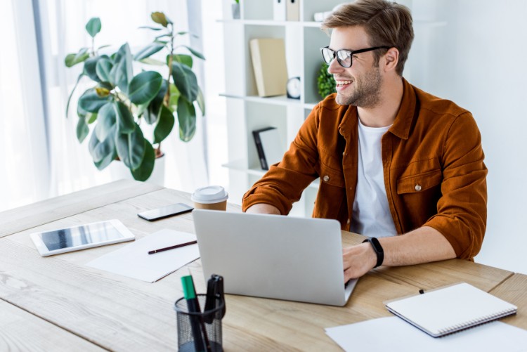 Man Works On A Laptop Wearing Glasses